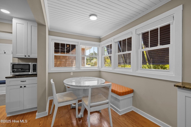 dining space with baseboards, light wood-style floors, and ornamental molding