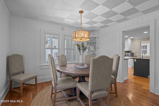 dining area with a healthy amount of sunlight, crown molding, and light wood-style flooring