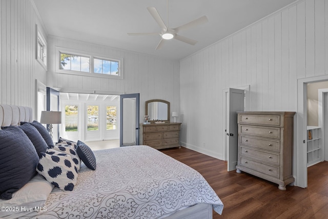 bedroom with dark wood finished floors, wood walls, and ceiling fan
