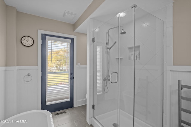 bathroom with wainscoting, a soaking tub, visible vents, and a shower stall