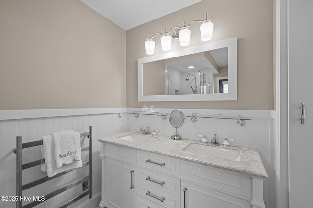 full bathroom featuring wainscoting, a sink, a shower, and double vanity