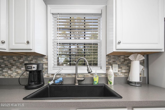 kitchen featuring white cabinets, tasteful backsplash, a sink, and a healthy amount of sunlight