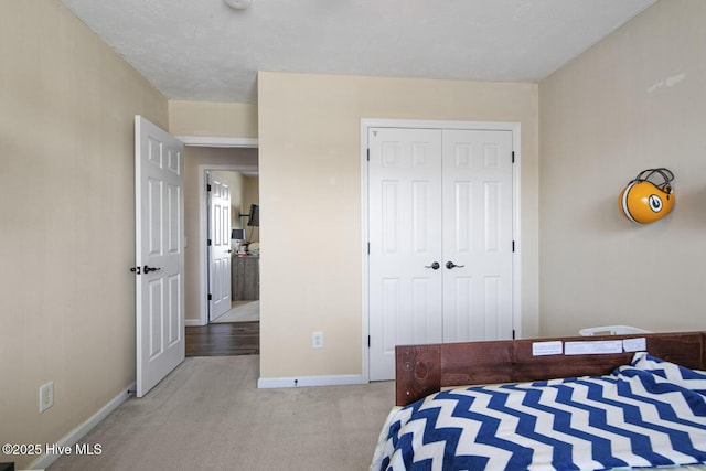 carpeted bedroom with a closet and baseboards