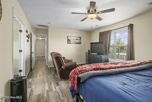 bedroom with wood finished floors, baseboards, a ceiling fan, and visible vents