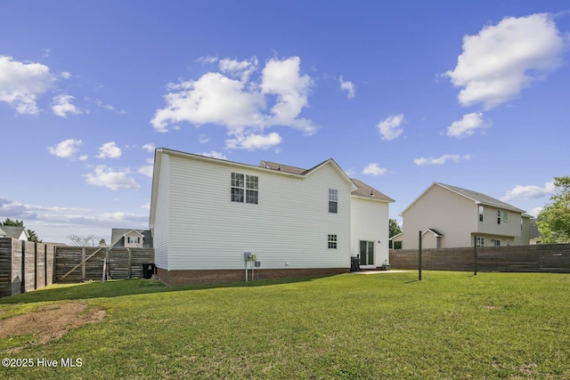 rear view of property featuring a yard and a fenced backyard