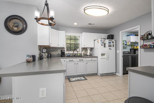 kitchen featuring white cabinets, a sink, white refrigerator with ice dispenser, washer and clothes dryer, and decorative backsplash