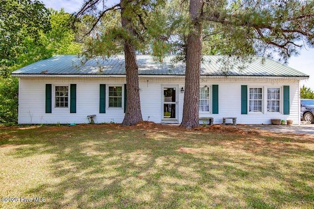 ranch-style house featuring driveway, metal roof, and a front lawn