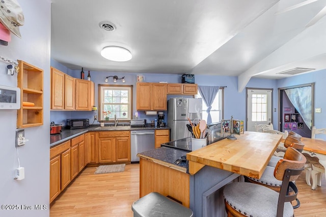 kitchen with a kitchen bar, visible vents, appliances with stainless steel finishes, a sink, and light wood-style floors