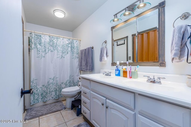 bathroom featuring double vanity, a sink, tile patterned flooring, and toilet