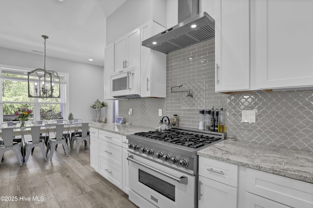 732 Avila Ave, Hampstead, NC 28443 - kitchen featuring range with gas stovetop, wall chimney range hood, white microwave, white cabinets, and tasteful backsplash