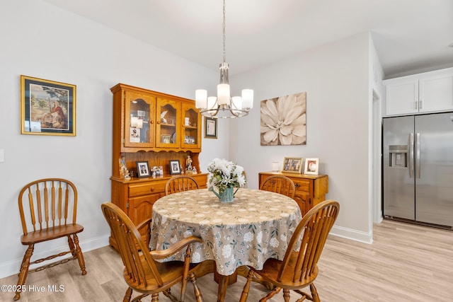 dining room featuring light wood-style floors, a notable chandelier, and baseboards
