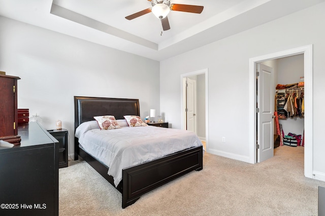 bedroom featuring a tray ceiling, baseboards, a spacious closet, and carpet floors
