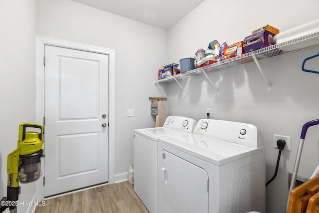 clothes washing area with light wood-type flooring, washer and dryer, and laundry area
