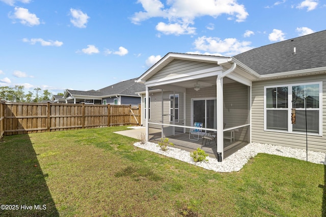rear view of house with a sunroom, a fenced backyard, a ceiling fan, a lawn, and a patio area
