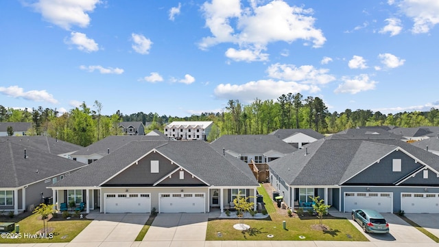 view of front facade featuring a residential view, driveway, a front yard, a garage, and a shingled roof