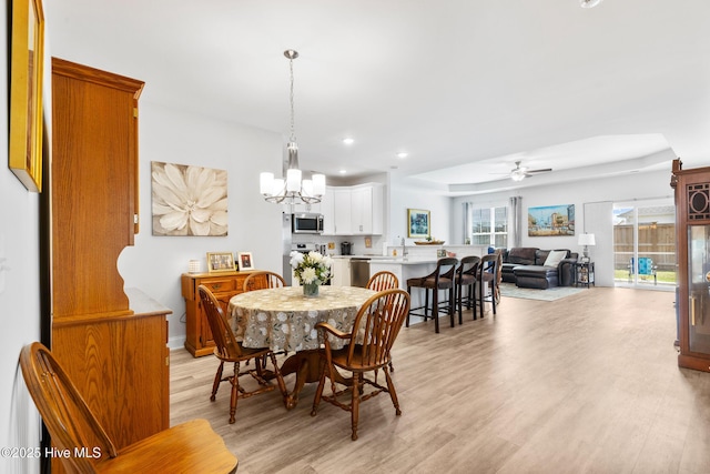 dining area with recessed lighting, light wood-style flooring, and ceiling fan with notable chandelier