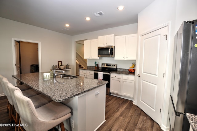kitchen with white cabinetry, recessed lighting, dark wood-type flooring, a sink, and appliances with stainless steel finishes