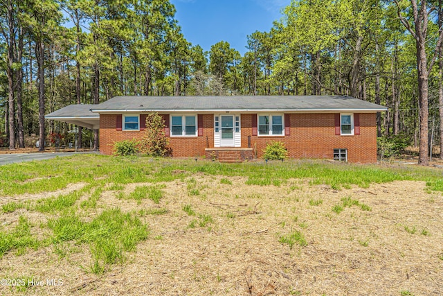 ranch-style home featuring brick siding, an attached carport, and driveway