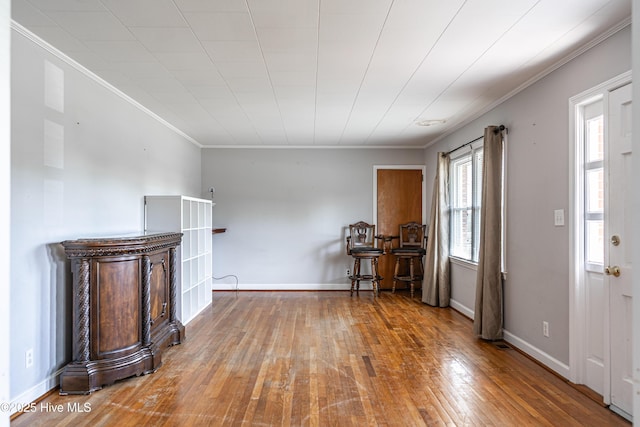 unfurnished living room with ornamental molding, hardwood / wood-style flooring, and baseboards