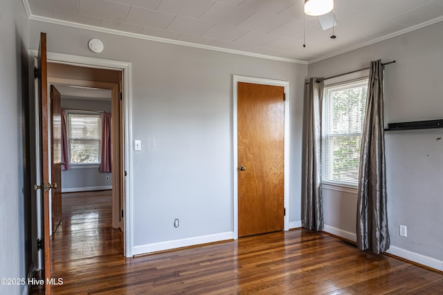 unfurnished bedroom featuring visible vents, ornamental molding, baseboards, and wood finished floors