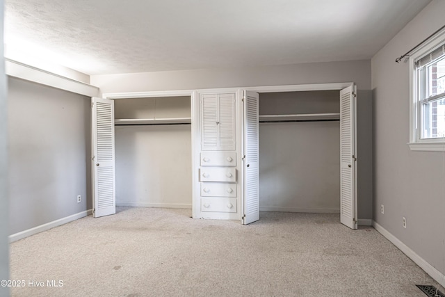 unfurnished bedroom featuring baseboards, multiple closets, visible vents, and carpet