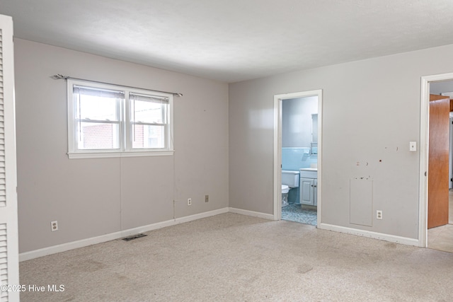 unfurnished bedroom with carpet floors, connected bathroom, baseboards, and visible vents
