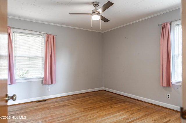 spare room featuring a wealth of natural light, crown molding, light wood finished floors, and visible vents