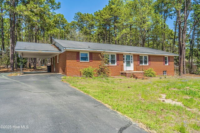single story home with brick siding, driveway, a carport, and a front lawn