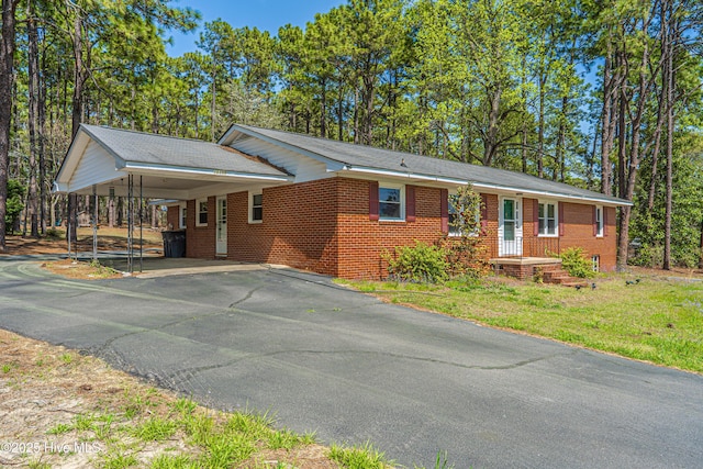 ranch-style house with a front lawn, driveway, a carport, and brick siding