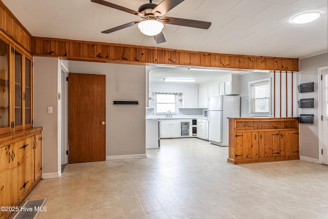 interior space with a sink, dishwasher, visible vents, freestanding refrigerator, and a ceiling fan