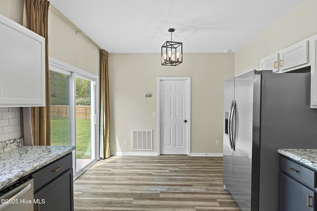 kitchen featuring tasteful backsplash, visible vents, a notable chandelier, stainless steel appliances, and light wood-style flooring