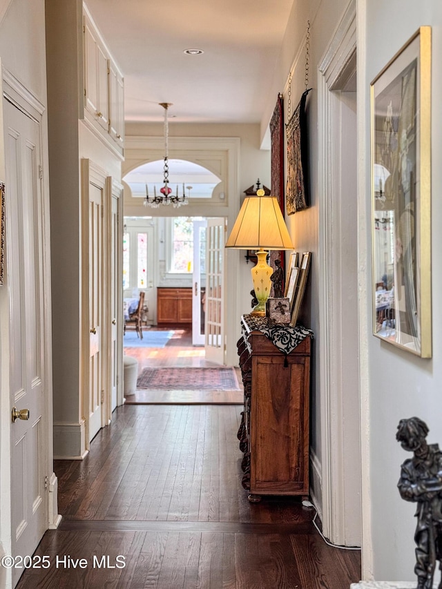 corridor with an inviting chandelier and dark wood finished floors