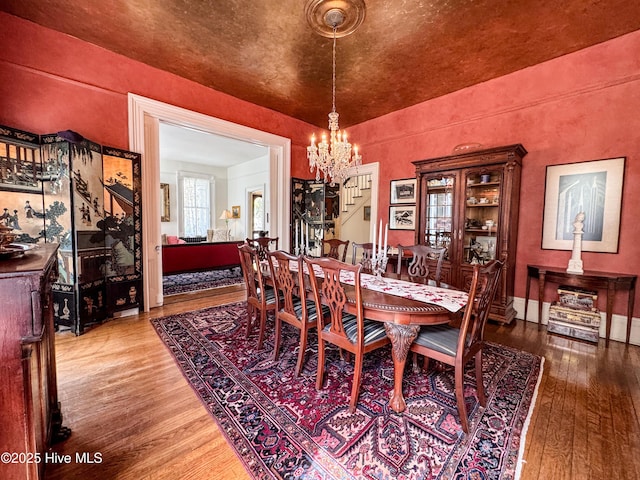 dining area with a chandelier, stairs, and hardwood / wood-style flooring