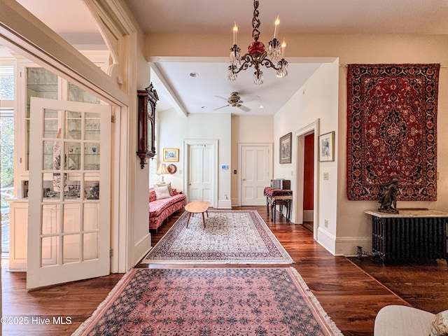 foyer with ceiling fan with notable chandelier, baseboards, and dark wood-style floors