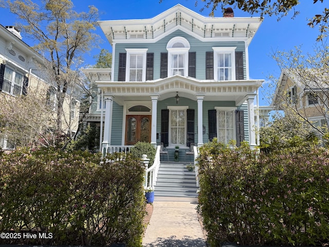 italianate-style house with a chimney, stairway, and a porch