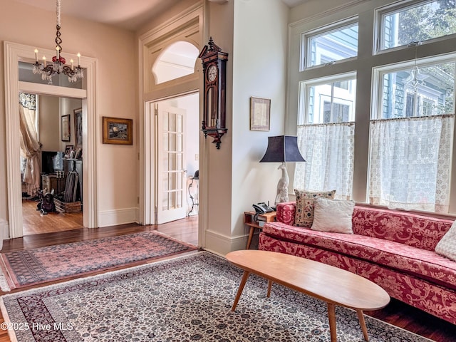 living area with a chandelier, wood finished floors, a high ceiling, and baseboards