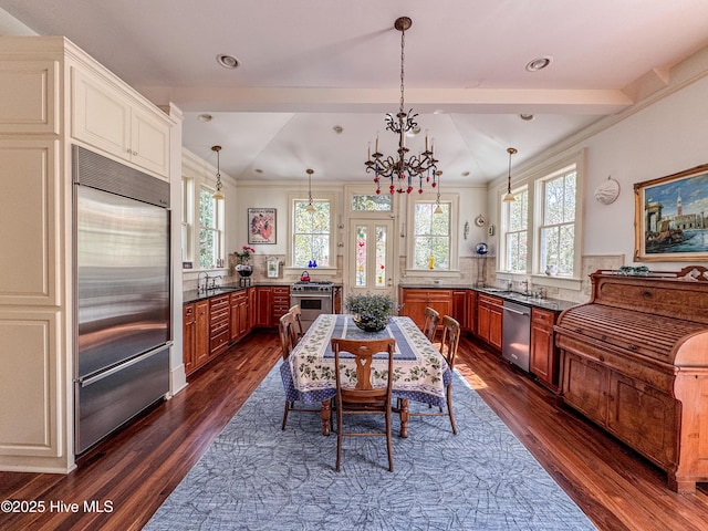 kitchen with dark wood finished floors, appliances with stainless steel finishes, pendant lighting, and a notable chandelier