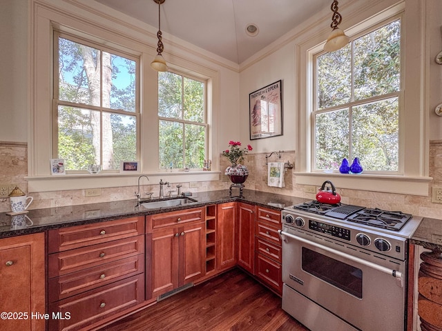 kitchen with brown cabinets, stainless steel gas range, dark stone counters, and a sink