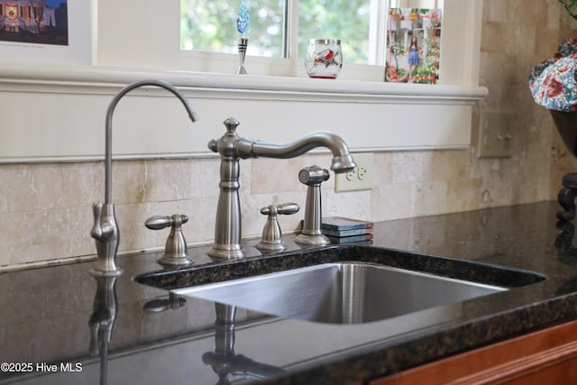 room details featuring dark stone counters, backsplash, and a sink
