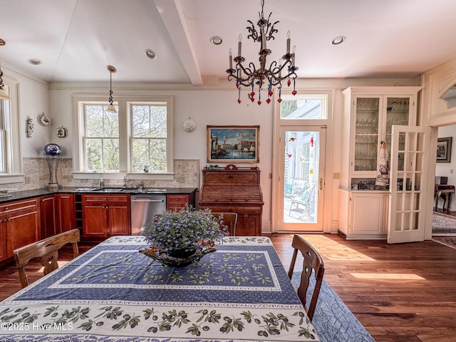 kitchen with stainless steel dishwasher, a chandelier, backsplash, and dark wood finished floors