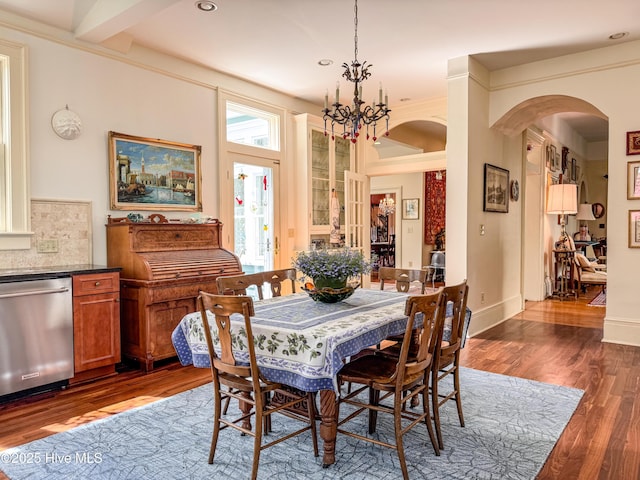 dining area with an inviting chandelier, arched walkways, recessed lighting, and dark wood finished floors