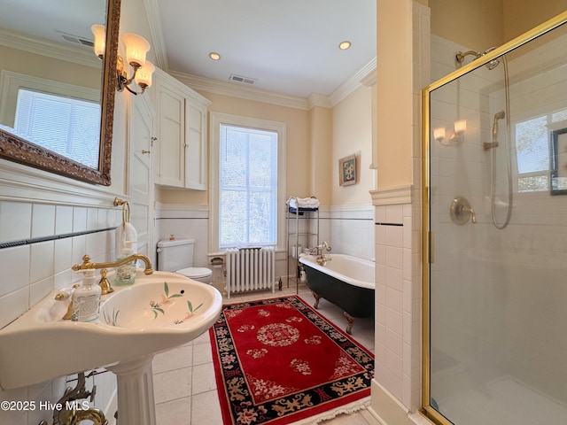 full bathroom featuring a shower stall, radiator, a freestanding tub, and visible vents