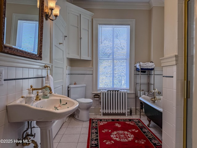 full bath with radiator heating unit, toilet, ornamental molding, wainscoting, and a bathtub