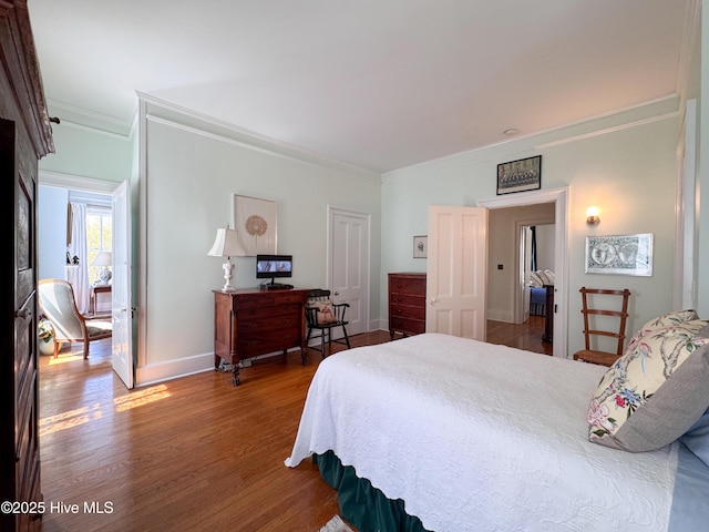 bedroom with wood finished floors, baseboards, and ornamental molding