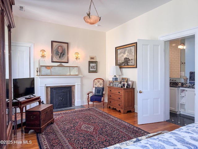 sitting room featuring baseboards, wood finished floors, visible vents, and a fireplace