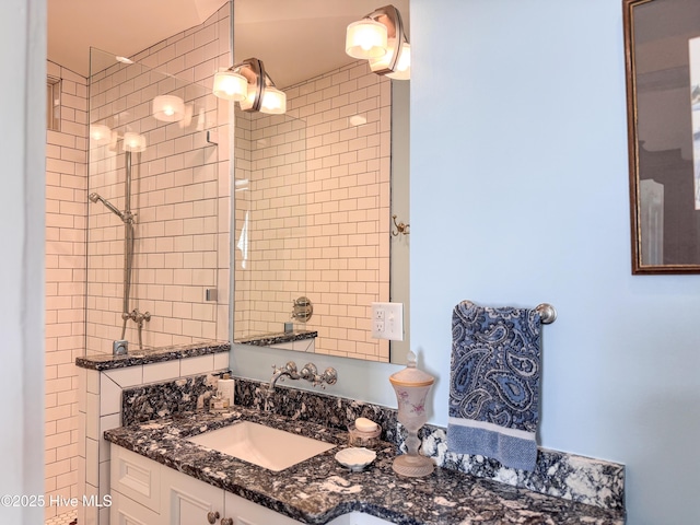 full bathroom with a tile shower and vanity