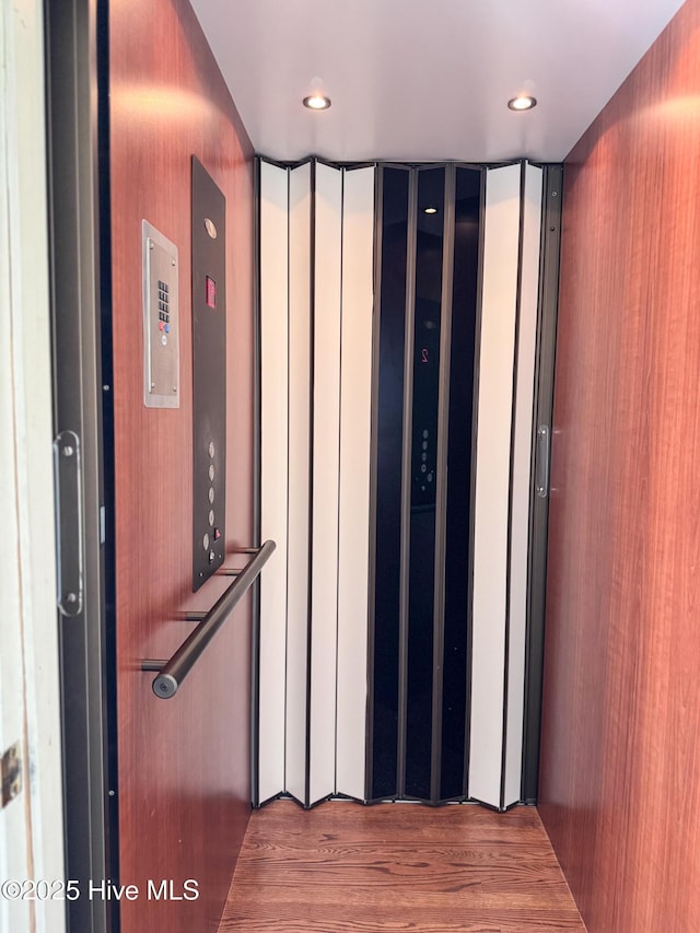 room details featuring recessed lighting, elevator, and wood finished floors