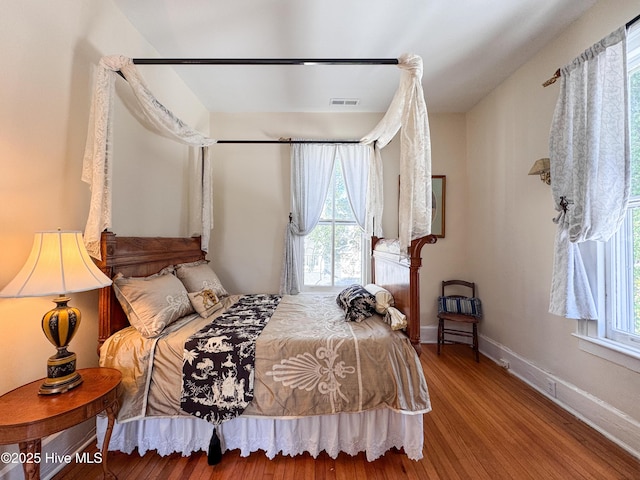bedroom featuring visible vents, baseboards, and wood finished floors