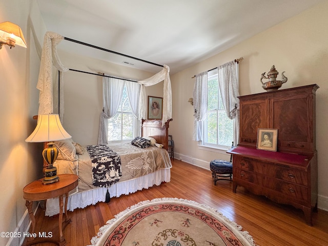 bedroom featuring wood finished floors, visible vents, and baseboards