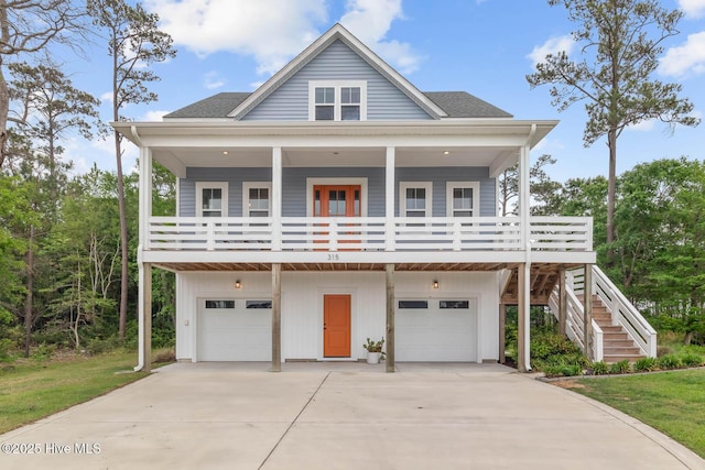 raised beach house featuring covered porch, an attached garage, stairs, and driveway